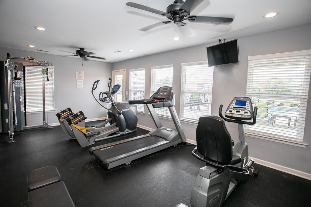 the gym has plenty of exercise equipment and a tv