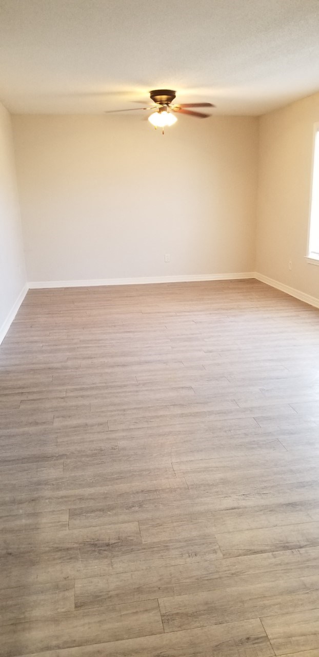 an empty living room with wood floors and a ceiling fan