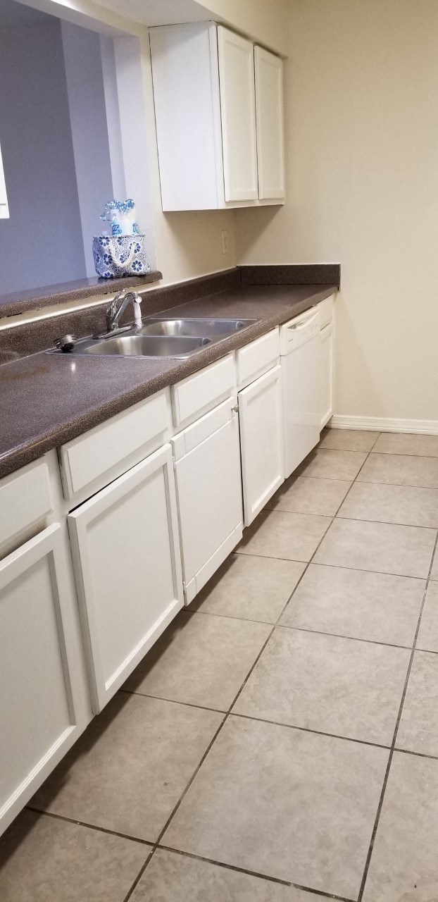 an empty kitchen with white cabinets and a sink