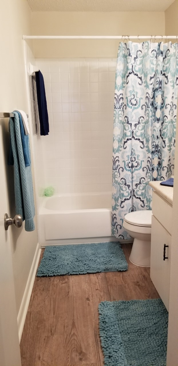 a bathroom with a shower and a toilet and a blue rug