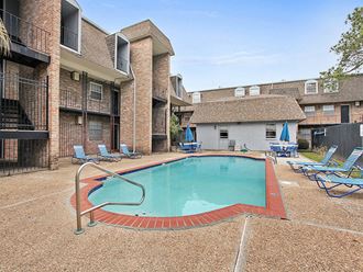 an outdoor pool with blue chairs and a brick building