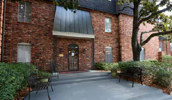 a brick building with a patio and chairs