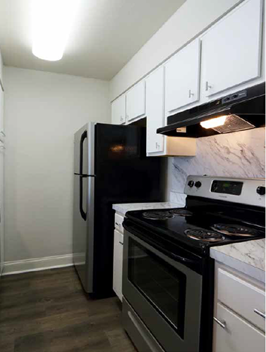 a kitchen with a stove refrigerator and white cabinets