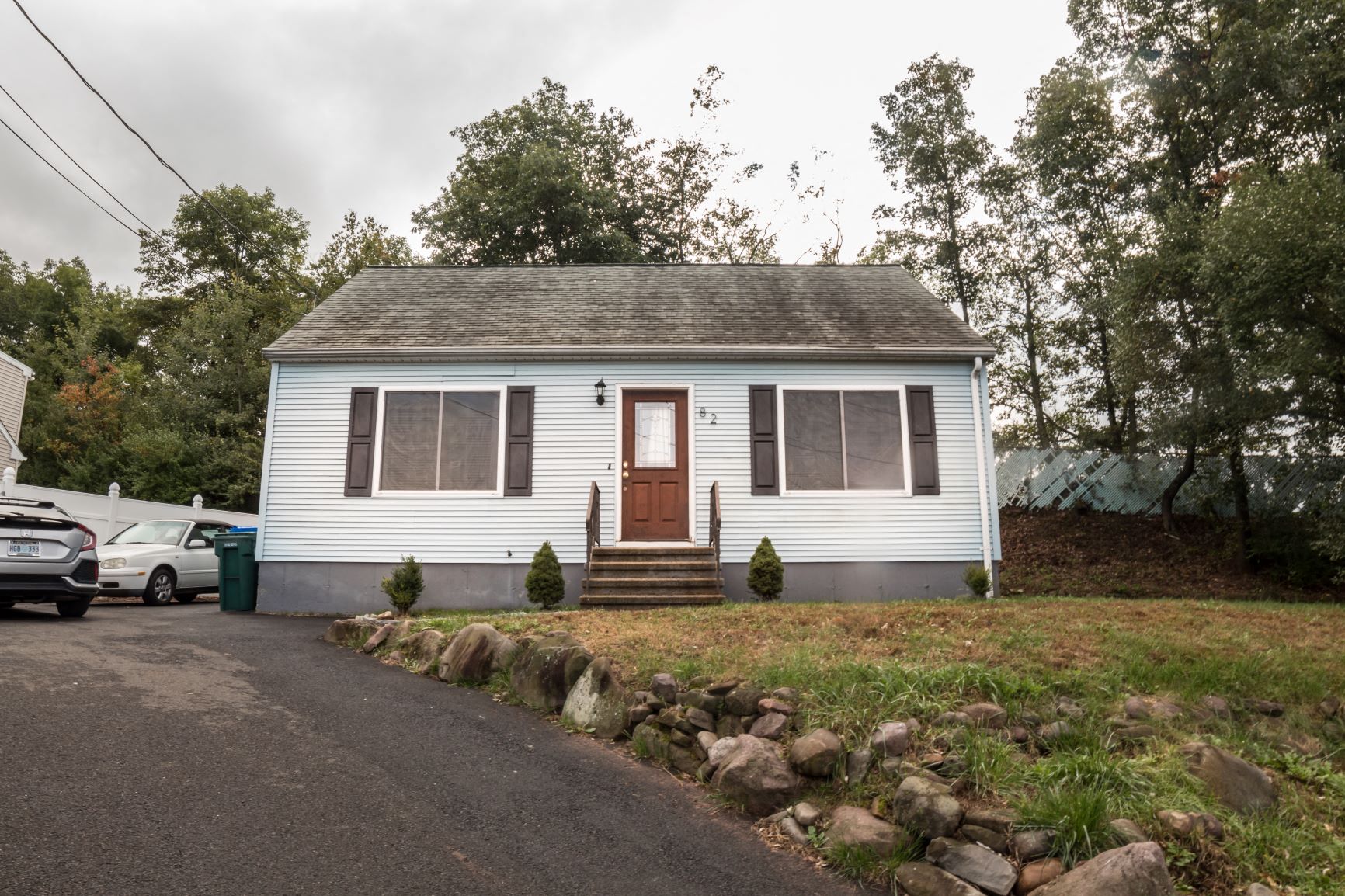 a white house with a brown door and a gravel driveway