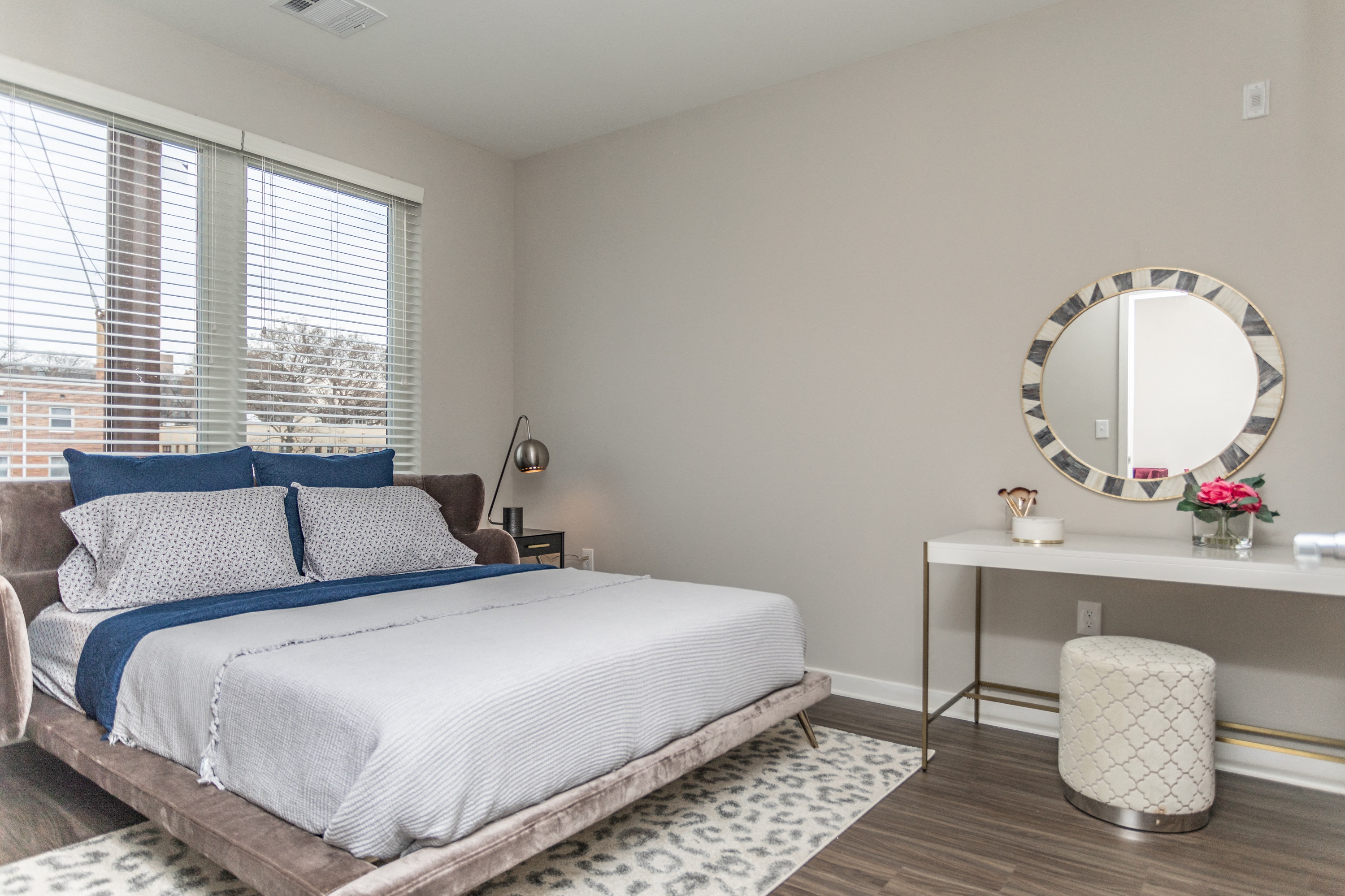 Gorgeous master bedroom with large window, hardwood flooring, and white walls