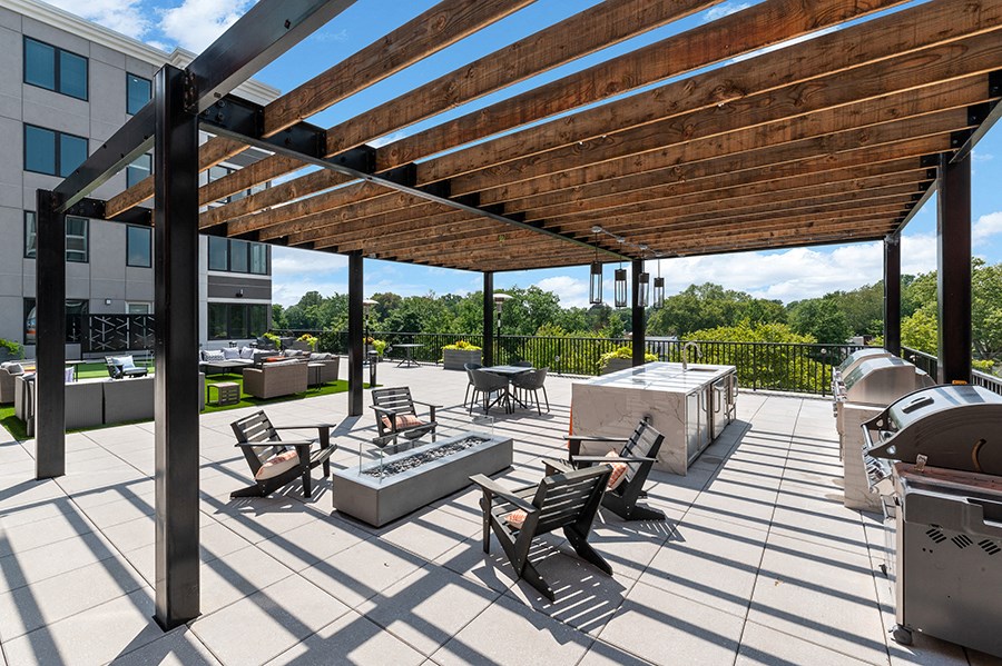 Outdoor sun deck with grill and seating areas under a pergola