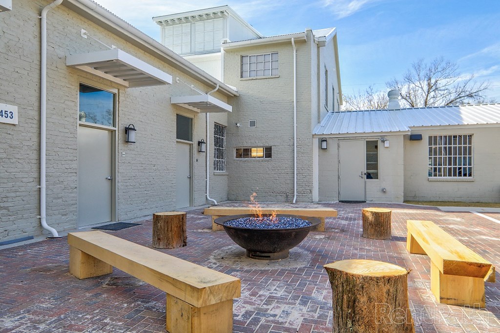 a courtyard with benches and a fire pit in front of a building