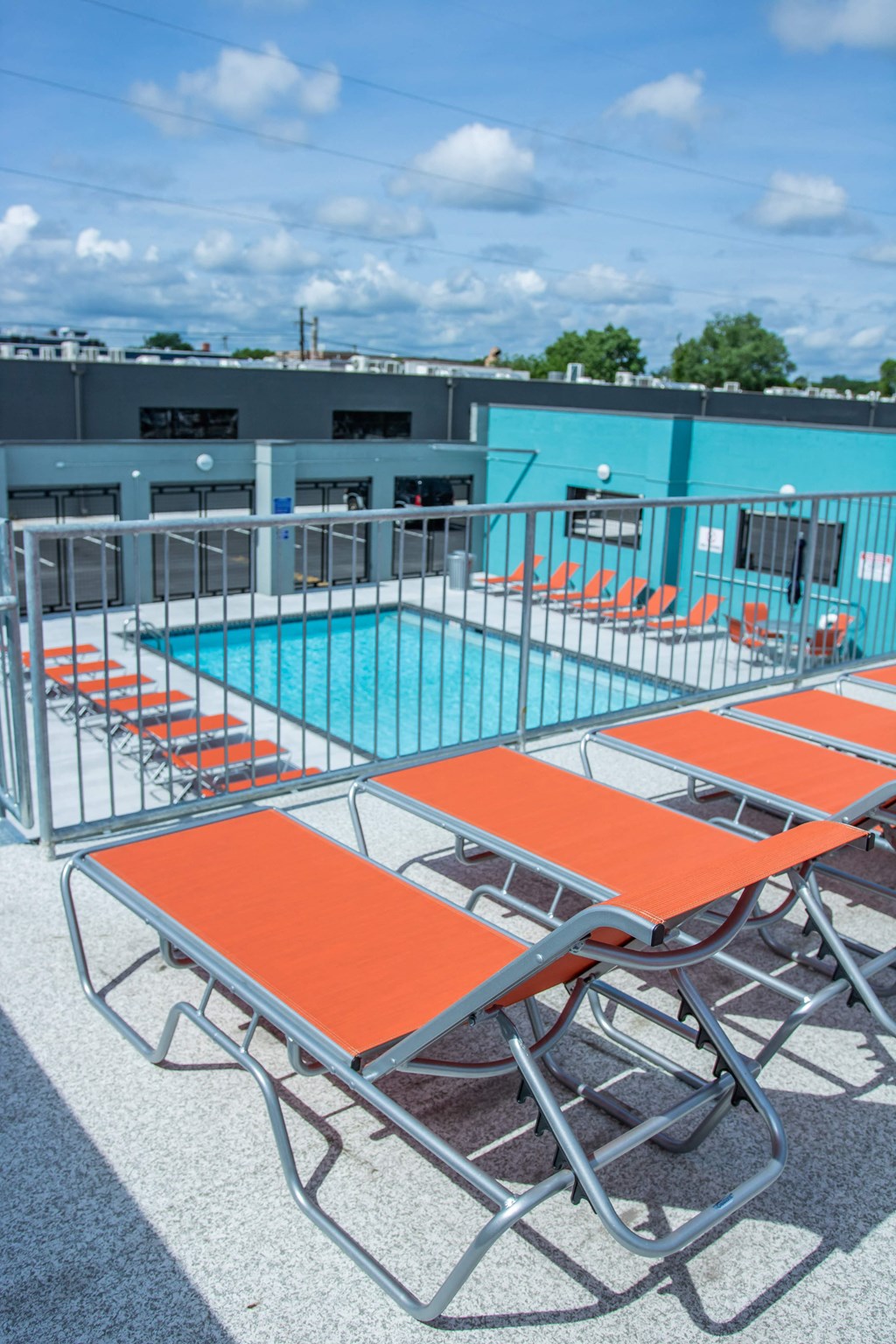 a pool with orange tables and chairs in front of a blue building
