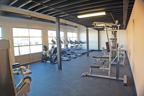 a gym with cardio equipment and weights on the floor
