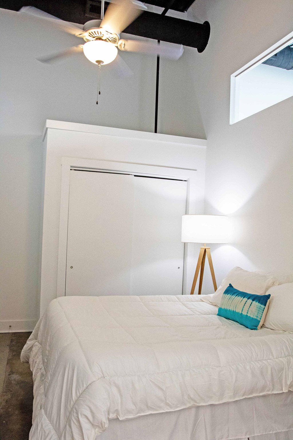 a bedroom with a white bed and a ceiling fan