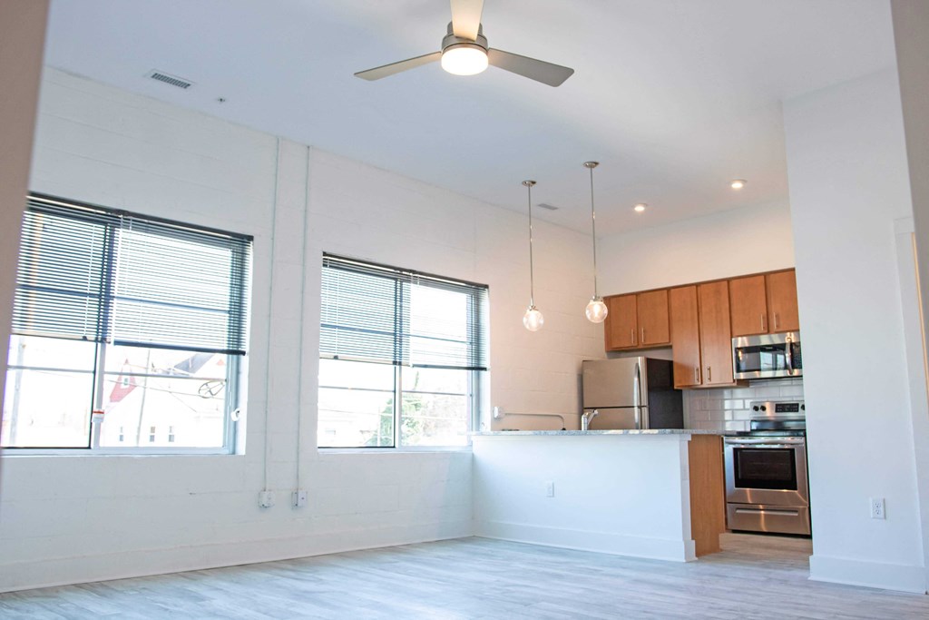 an empty living room and kitchen with a ceiling fan