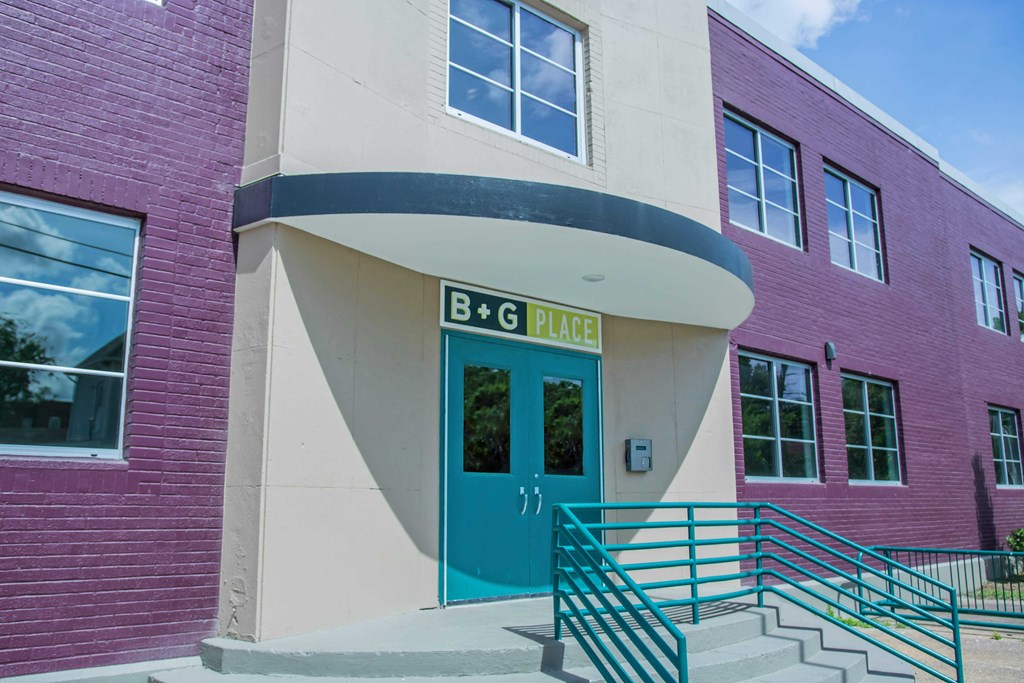 a pink building with a blue door and stairs