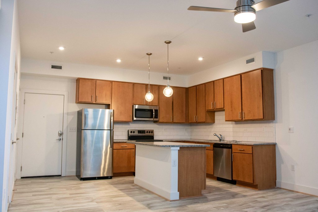 an empty kitchen with stainless steel appliances and wooden cabinets