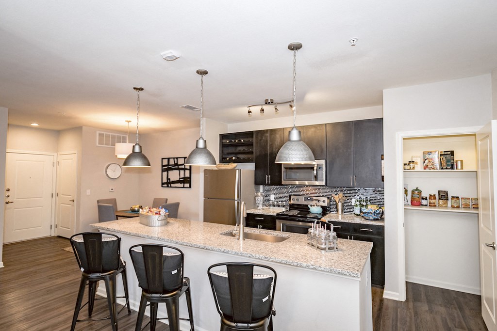 a kitchen with a large counter top with three bar stools