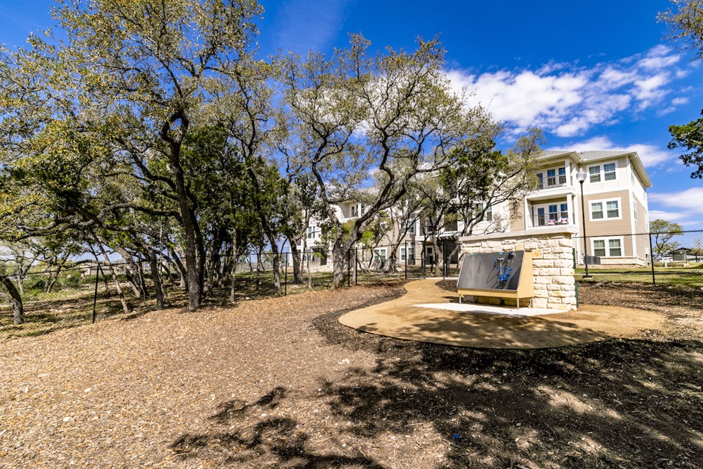 the entrance to a park with trees and a monument