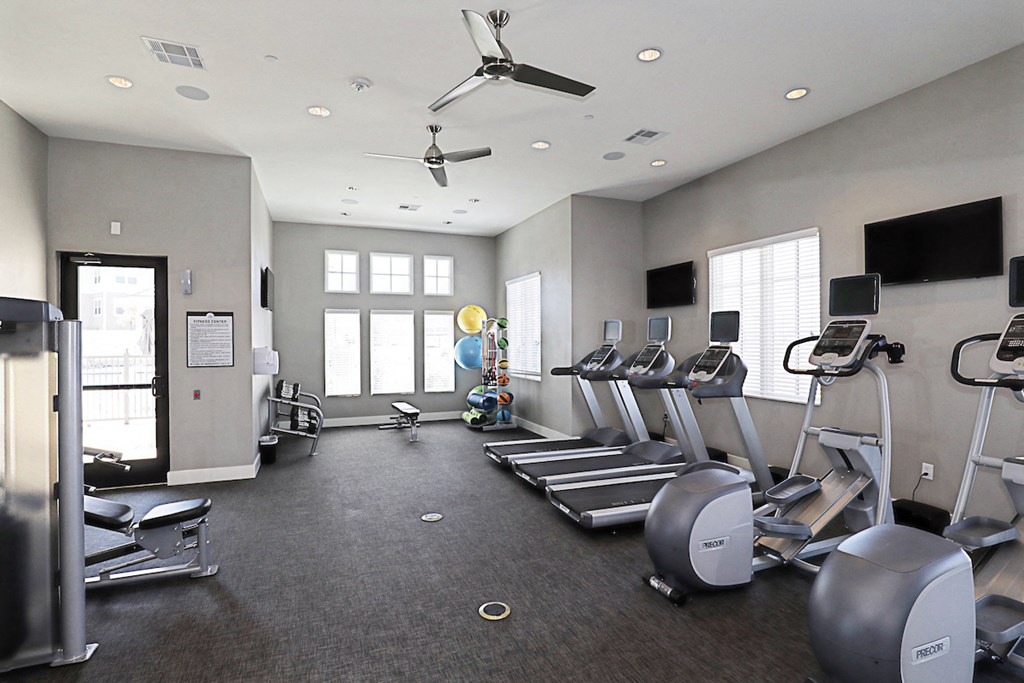 a gym with treadmills and other exercise equipment and a tv