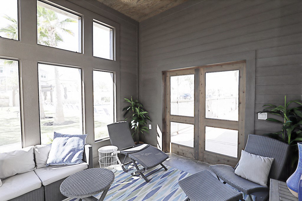 a screened porch with a couch and chairs and windows