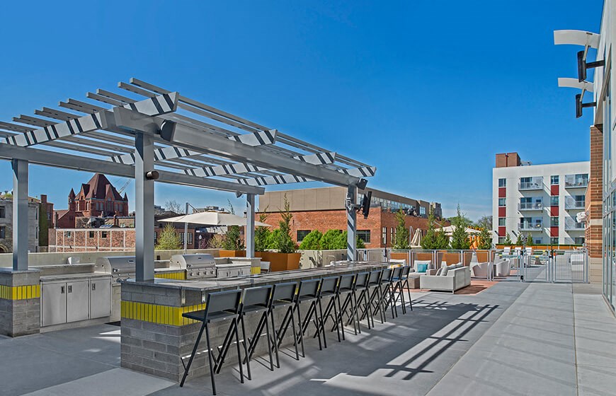 a patio with a bar and chairs and a building in the background