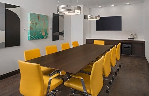 a conference room with a long wooden table and yellow chairs