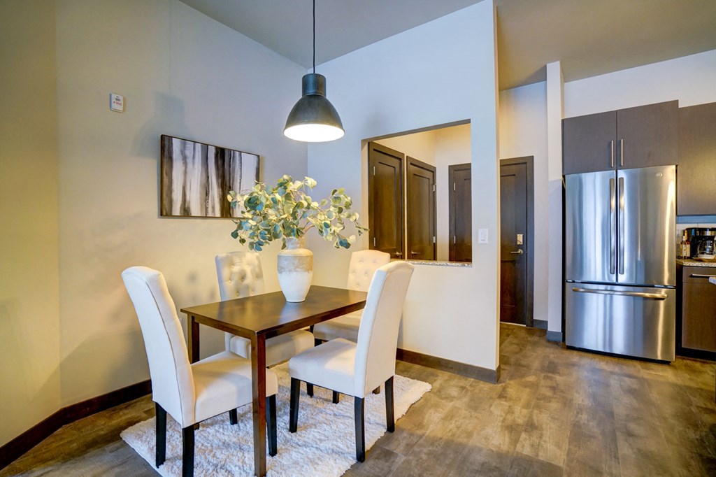 a dining room with a table and chairs and a stainless steel refrigerator