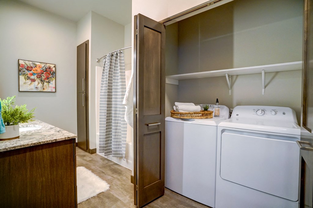 a washer and dryer in a laundry room with a closet and a shower