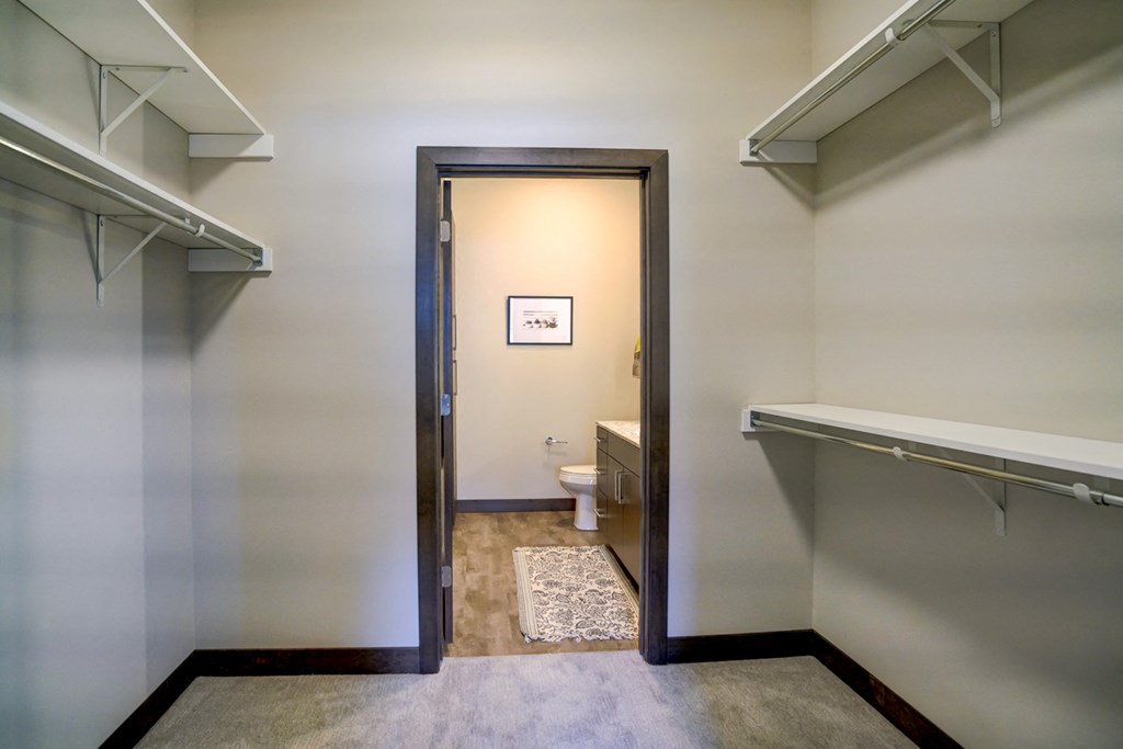 a walk in closet with a door open to a bathroom