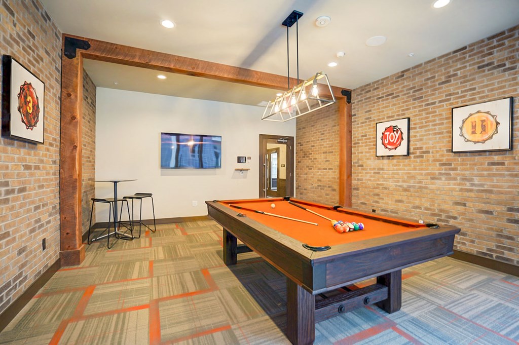 a pool table in a living room with a brick wall