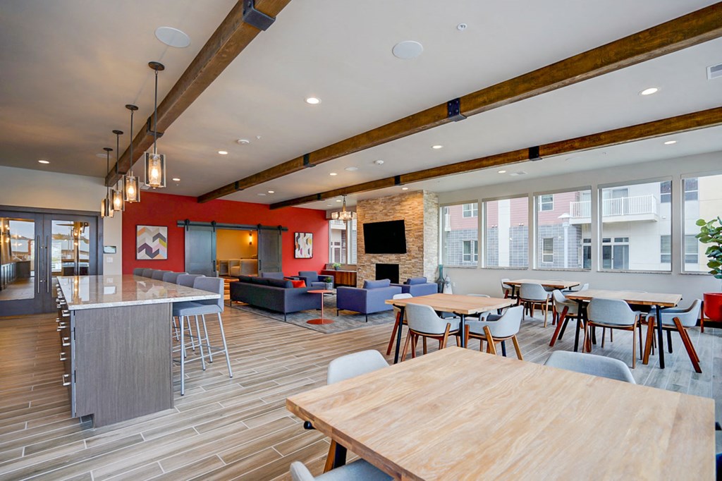 a communal area with tables and chairs and a kitchen and living room