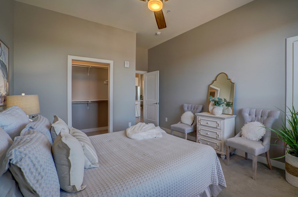 a bedroom with a bed and two chairs and a dresser