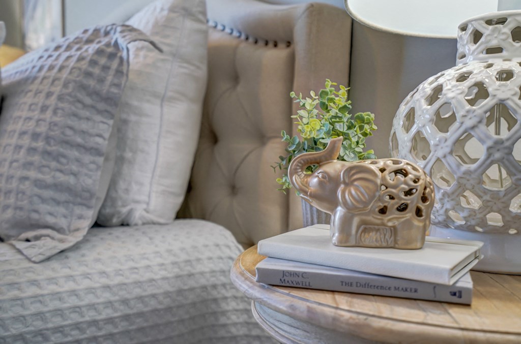 a stack of books and an elephant vase on a table next to a couch