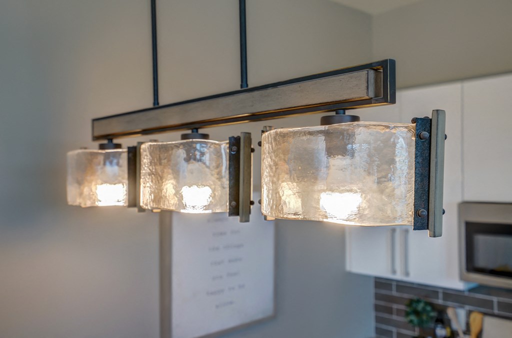 three lights hanging in a kitchen with white cabinets