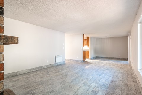 an empty living room with wood floors and white walls