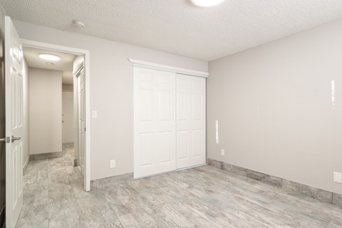 an empty room with a white door and a door to a closet