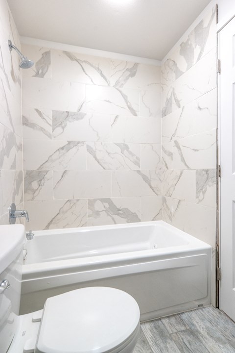 a white bathroom with a toilet and a bath tub