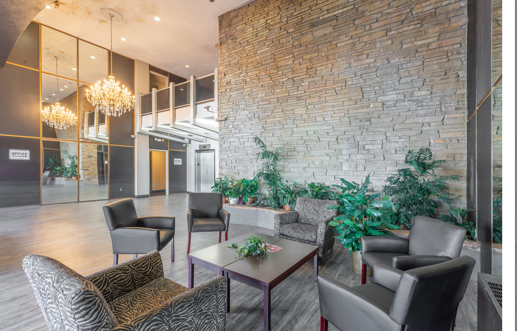 a lobby with chairs and a table and a brick wall
