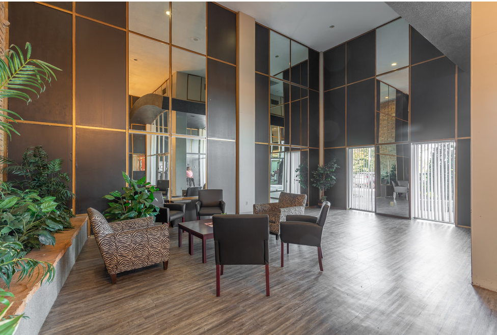 a lobby with a table and chairs and a glass wall