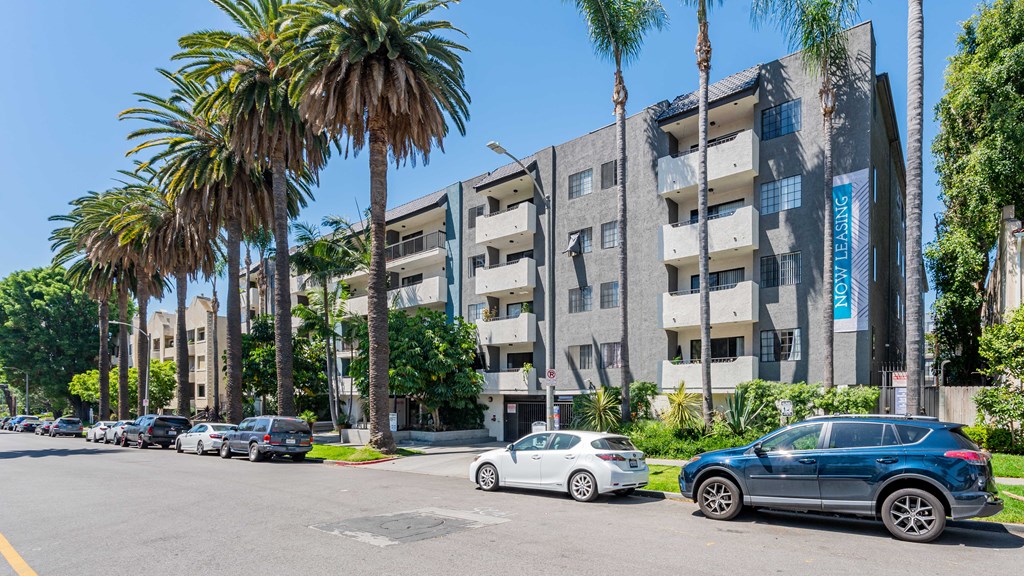 a city street with cars parked in front of an apartment building