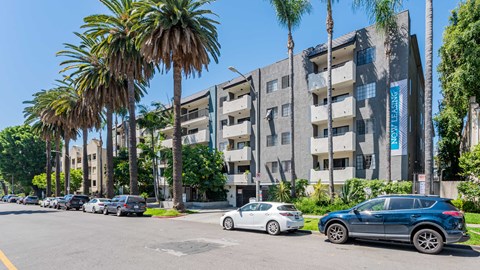 a city street with cars parked in front of an apartment building