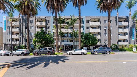 a street view of an apartment building with cars parked in front