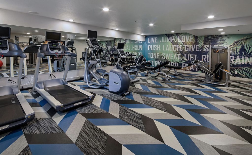 a gym with weights and cardio machines and a wall mural