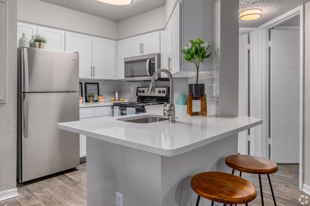 A modern kitchen with a refrigerator, sink, and stove.