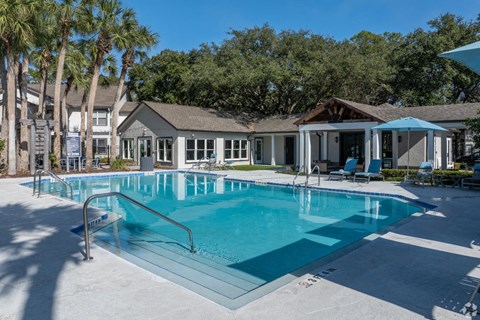 A swimming pool surrounded by palm trees and a building in the background.