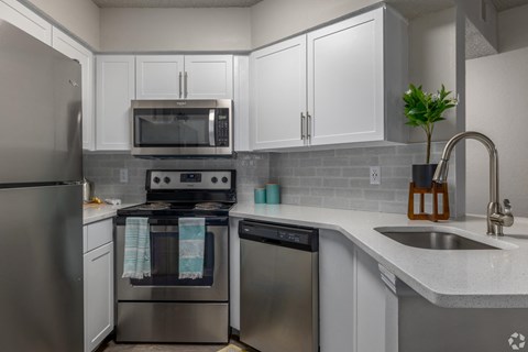 A modern kitchen with stainless steel appliances and white cabinets.