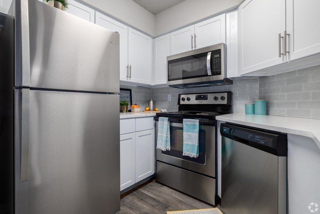 A kitchen with a stainless steel refrigerator and a microwave above the stove.