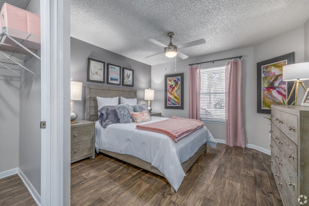 A bedroom with a bed, dresser, and ceiling fan.