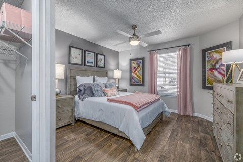 A bedroom with a bed, dresser, and ceiling fan.
