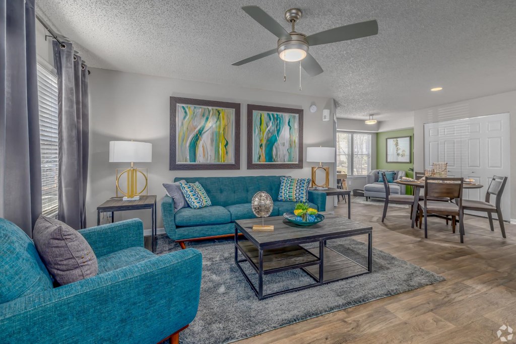 A living room with a blue couch and a ceiling fan.