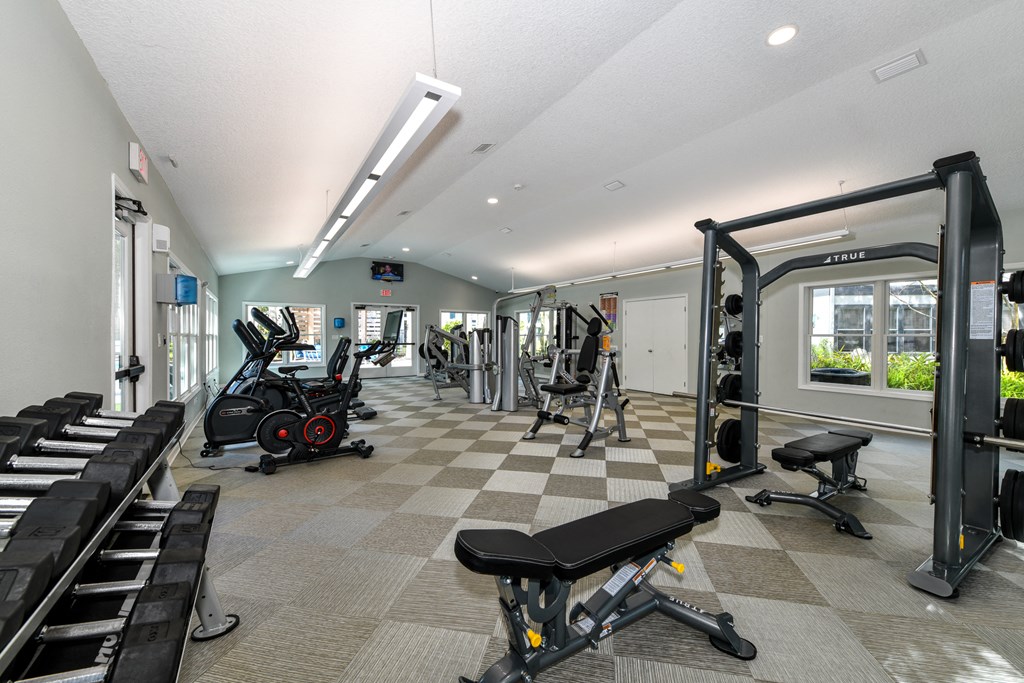 a gym with cardio equipment and weights on a checkered floor