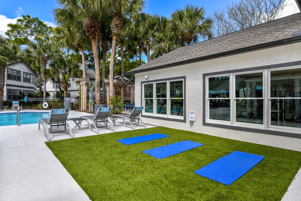 the yard has a pool and patio with chairs and grass