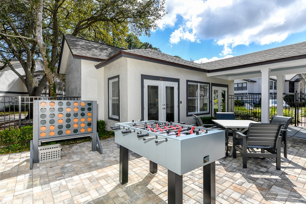a backyard with a foosball table and chairs and a house